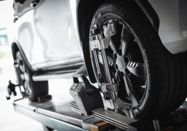 Technician performing wheel alignment on a car