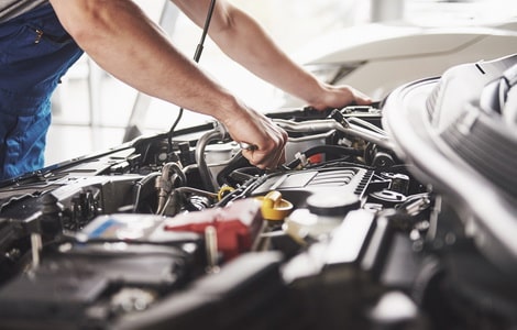 man checking under the hood of a car at an automobile repair shop